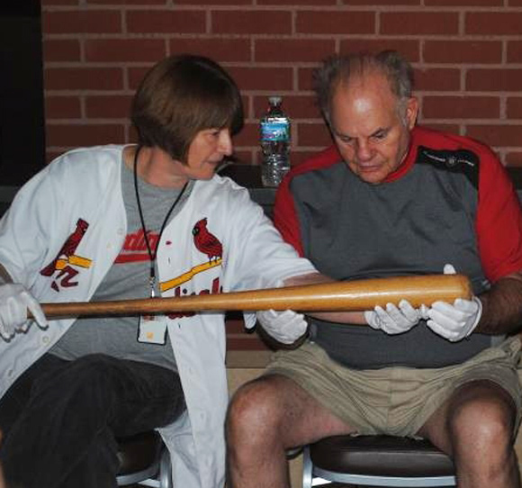 A volunteer assists a member of the Cardinals Reminiscence League in sparking his memory by examining memorabilia. Photo courtesy of SLU Media Relations