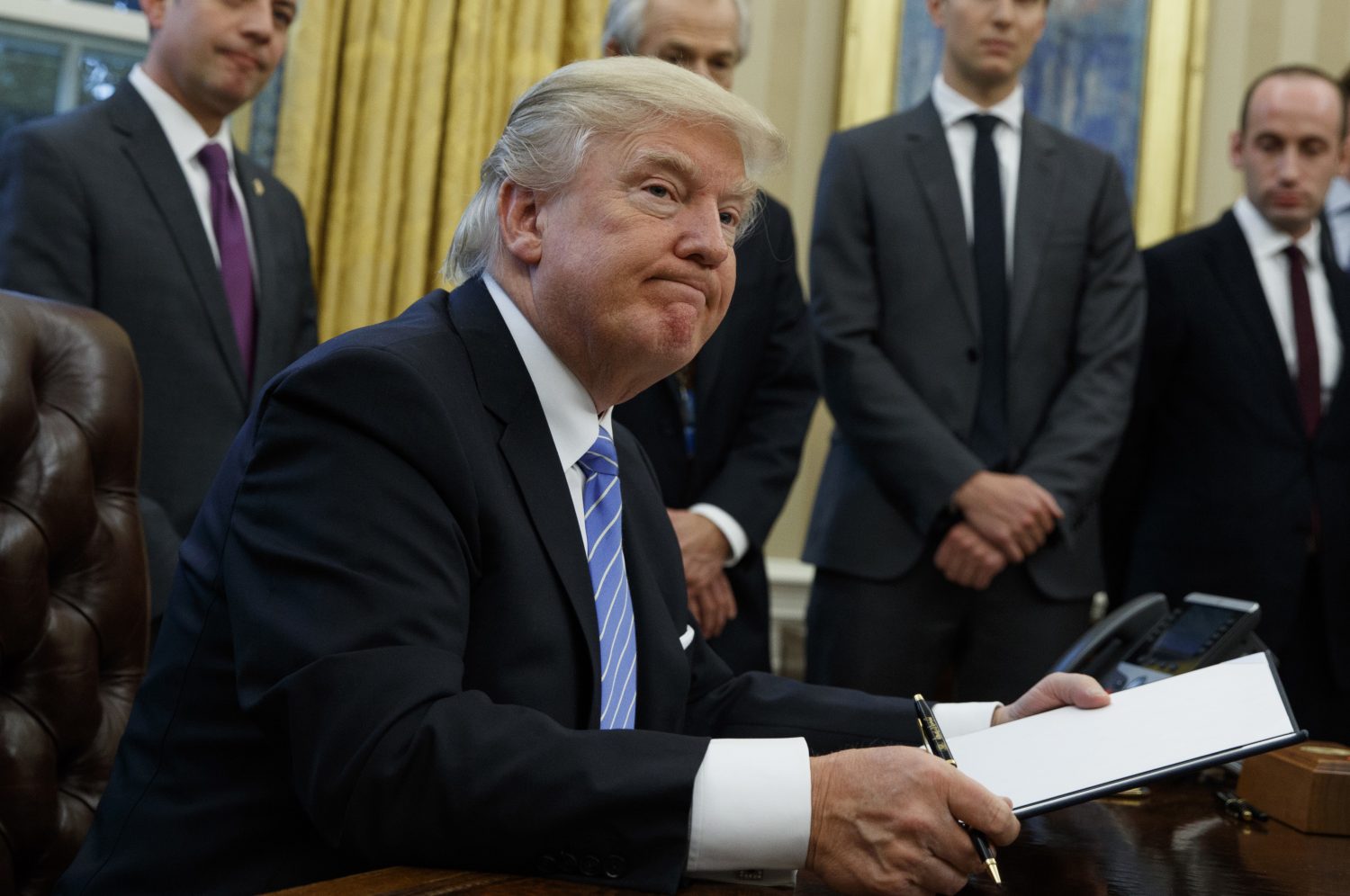 President Donald Trump looks up after signing the final of three executive orders, Monday, Jan. 23, 2017, in the Oval Office of the White House in Washington. (AP Photo/Evan Vucci)
