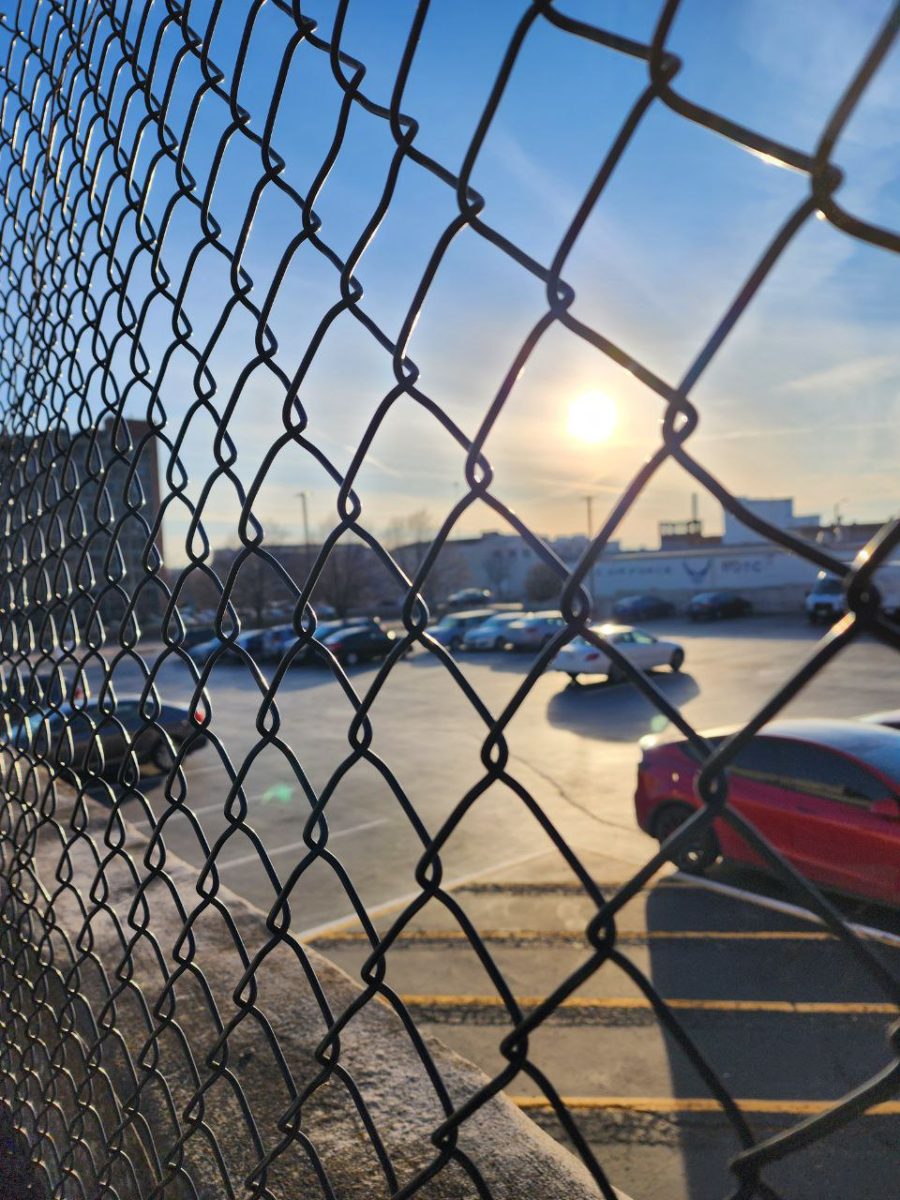 A SLU parking lot with a fence in front of it. 