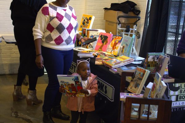  Patrons of High Low cafe and Left Bank Books browse the dozens of books placed on display on Sunday Feb. 18, 2024, in St. Louis, MO. A young child and parent are pictured at the book stand. 