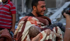 A man cries after pulling out a child from under the rubble in Gaza on Oct. 12, 2023.