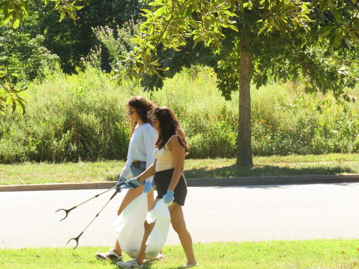 Two Chaifetz students engage in conversation as they keep an eye out for trash near the Dennis & Judith Jones Visitor and Education Center at Forest Park on Sept. 7, 2024.