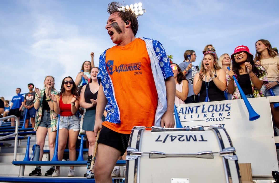 A picture of student Brendan Brunette banging a drum at the Saint Louis Universities women's soccer game against Brigham Young University on Aug. 22, 2024.