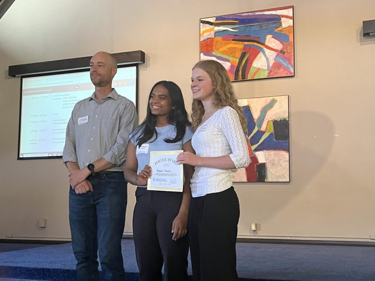 Undergraduate winners Julia Gaugel and Imandi Mendis pose for a photo with Dr. Blythe Janowiak as they accept their award at the Biology Symposium.