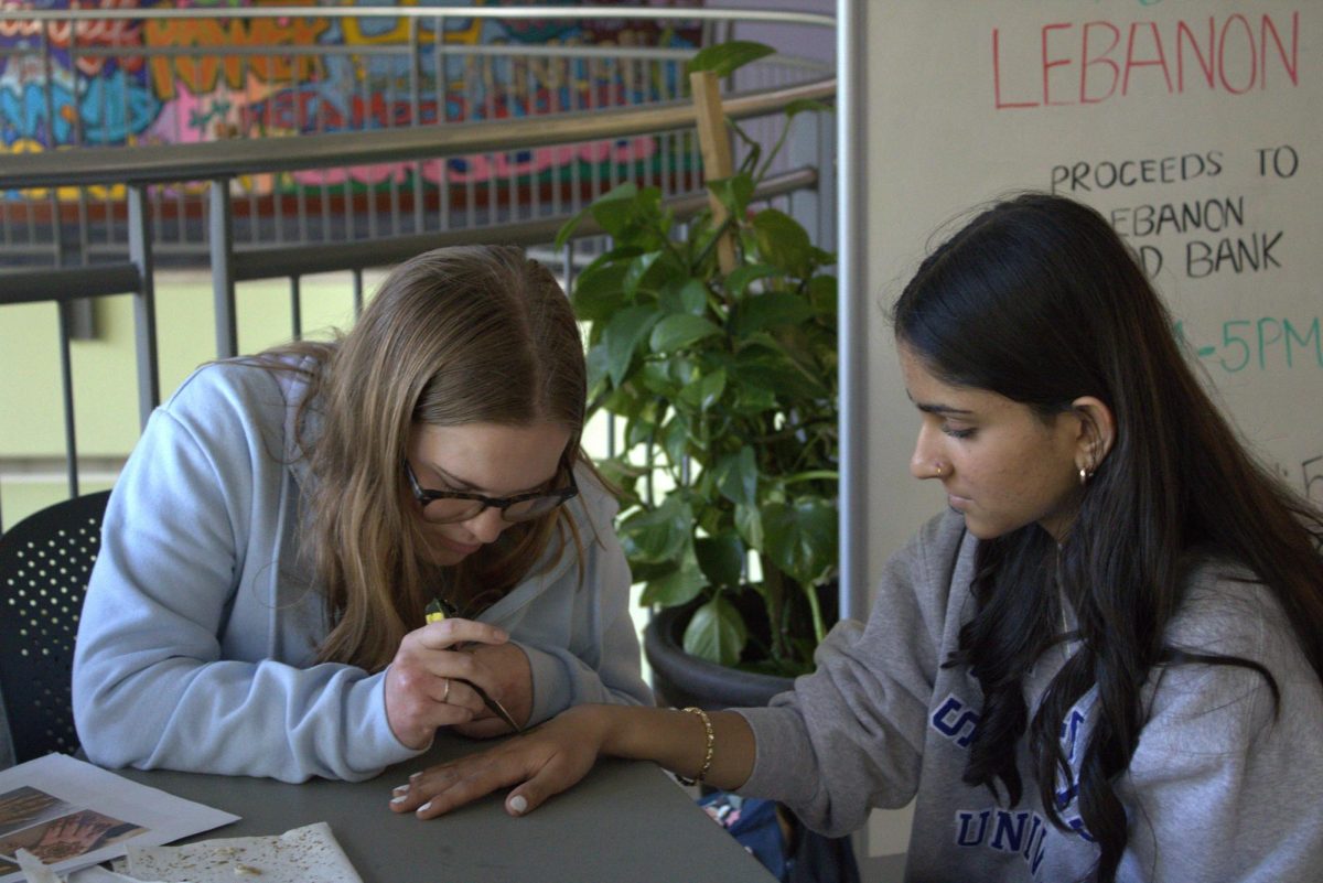 Assisting her roomates with the fundraiser, junior Kaia Monacoe does a henna design on freshman Piya Patel’s hand on Oct. 9, 2024. 