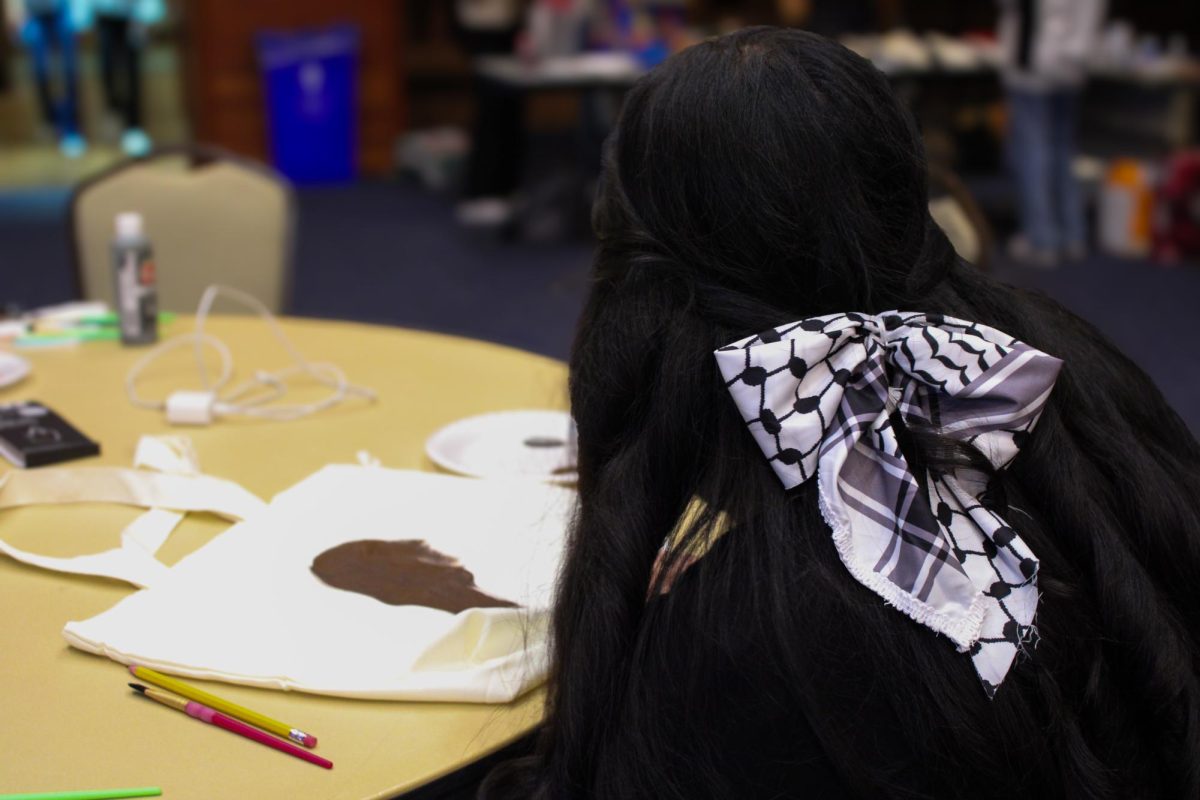 Freshman Fatima Amjed pictured wearing a keffiyeh bow and decorating a tote bag during the Middle Eastern Student Association's craft night on Oct. 10, 2024. 