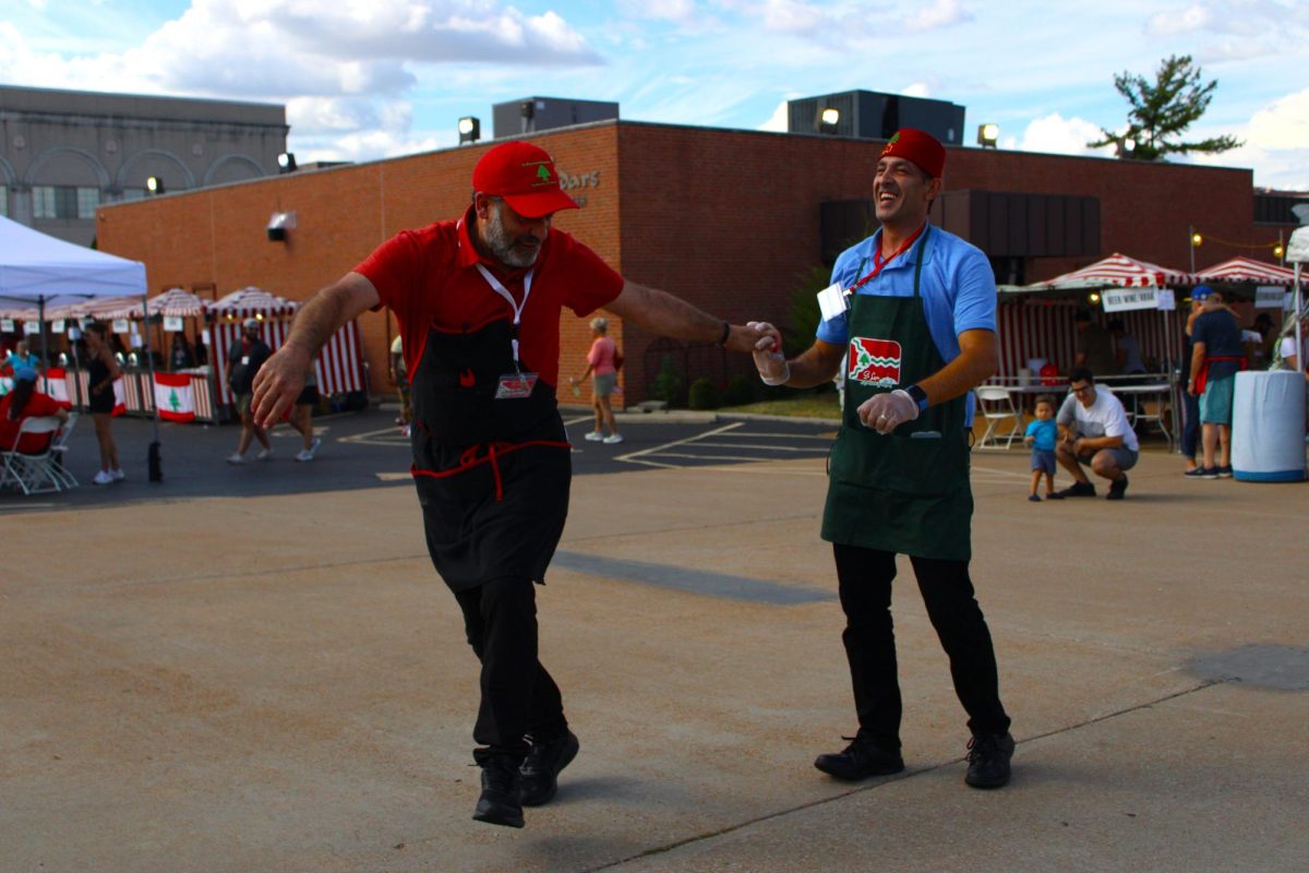 Two male volunteers hold hands while laughing and dancing Dabke at the 57th annual Lebanese Festival on Saturday Sept. 14, 2024, at the St. Raymond Maronite Cathedral in St. Louis, MO.