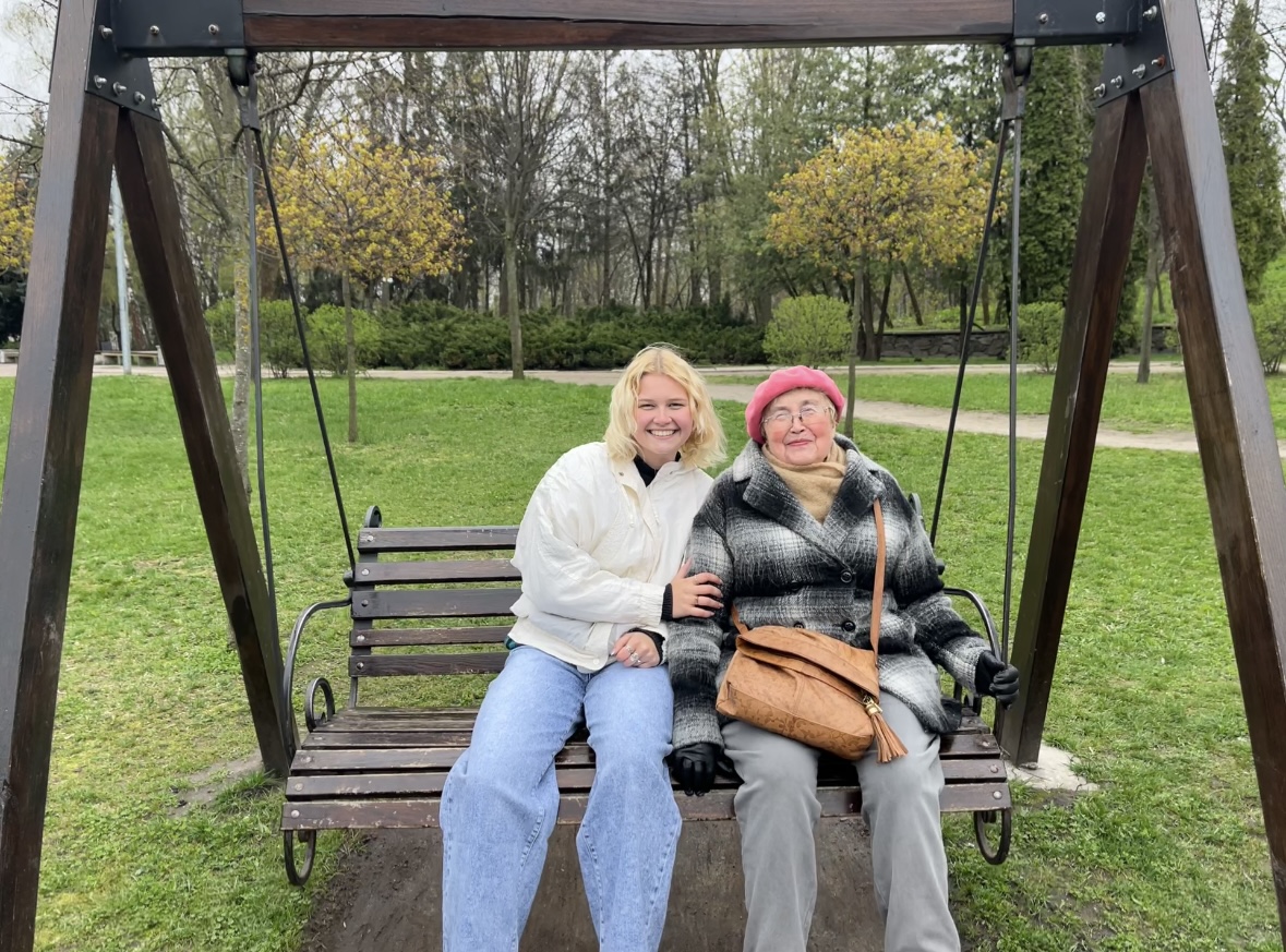 Mariya Yasinovska and her grandmother, Nadia Yarova, sitting on a park bench together during Mariya’s visit to Ukraine in March 2023. 