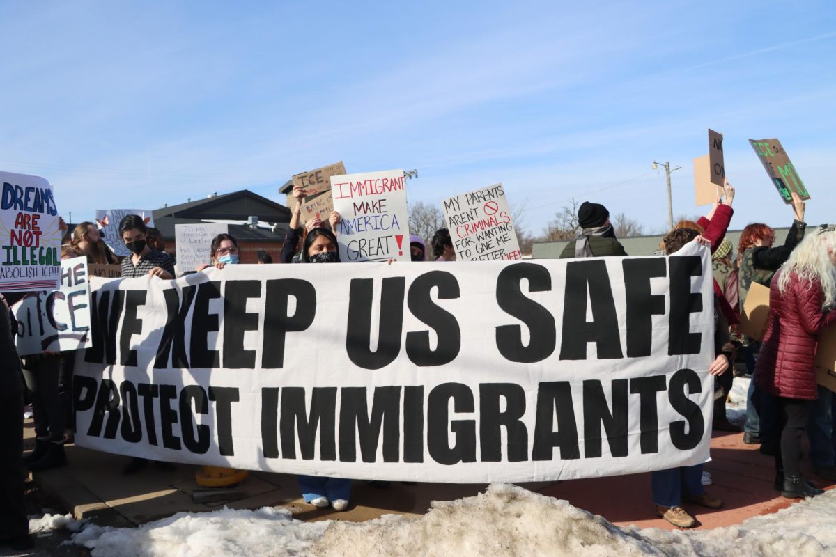 At a protest against ICE, attendees gather at the corner of Marlowe Avenue and Woodson Road with an "We Keep Us Safe, Protect Immigrants" banner on Jan. 25, 2025.