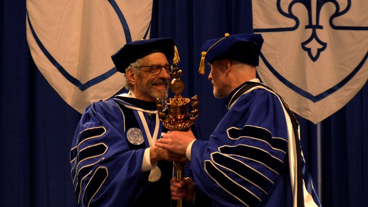 Former president, Fred Pestello, passes the university's mace to newly inaugurated President Edward Feser on Nov. 5, 2025 at Chaifetz Arena in St. Louis, Missouri.