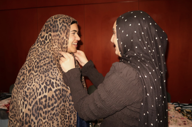 Saint Louis University students Layali Mutan, right, helps Fatima Amjed, left, try on a leopard print hijab on Feb. 17 in the Busch Student Center. 